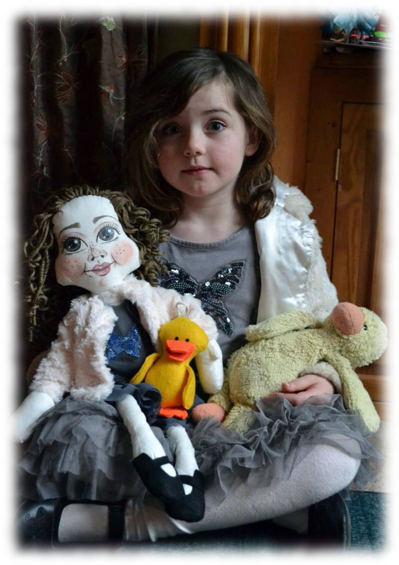Small girl holding a portrait doll of herself